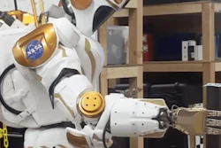 A NASA Valkyrie robot picks up an item with its hand.