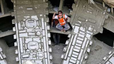 A worker pumps his fists as he stands between the cutting blades of a massive tunneling machine after it broke through a five-foot wide concrete wall to complete boring for the State Route 99 highway, Tuesday, April 4, 2017, under Seattle. After tunneling more than 9,000 feet and building an outer tunnel wall as it moved forward, the boring machine finished digging what will be a two-mile, double-decker traffic tunnel to replace the Alaskan Way viaduct, damaged in an earthquake in 2001.