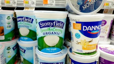Stonyfield and Dannon yogurts are stacked on a supermarket shelf, Tuesday, April 4, 2017, in New York. Danone will sell its Stonyfield Farms business to gain approval from the U.S. for a $12.5 billion buyout of Denver's WhiteWave Foods, doubling the size of the French company's business in North America.