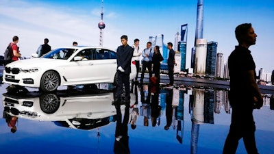 In this April 19, 2017, file photo, visitors look at a BMW 5 series vehicle displayed at the Auto Shanghai 2017 show at the National Exhibition and Convention Center in Shanghai, China. The China Association of Automobile Manufacturers said Thursday, May 11, 2017 that China's auto sales shrank in April as demand for most types of vehicles wilted.