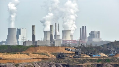 In this April 3, 2014 file photo giant machines dig for brown coal at the open-cast mining Garzweiler in front of a smoking power plant near the city of Grevenbroich in western Germany. Despite uncertainties about whether the United States will remain committed to the Paris climate accord under President Donald Trump, diplomats convened talks in Bonn, Germany, Monday, May 8, 2017 on implementing the details of the global deal to combat global warming.