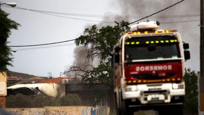 A firefighter truck leaves as smoke rises from a factory after several explosions, in Arganda del Rey, outside Madrid, Thursday, May 4, 2017. A fire and several explosions ripped through an industrial waste treatment factory Thursday in a town near Madrid, sending 30 people to the hospital for treatment and forcing the immediate evacuation of nearby schools and offices, officials said.