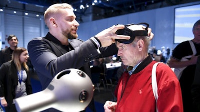 Nokia's Mikko Korhonen, left, demonstrates to Pauli Kuikka how to use the OZO Virtual Reality camera before a the general meeting of the Finnish telecommunication network company Nokia in Helsinki, Tuesday May 23, 2017. Nokia and Apple have settled their numerous legal disputes after signing an agreement to work together. Nokia, once the world's No. 1 cellphone maker and now a networks provider after selling its ailing mobile phone sector to Microsoft in 2014, described the pact as 'meaningful.'