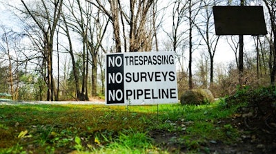 In this April 20, 2017 photo, a sign opposing a proposed pipeline sits in the front yard of a house in Green, Ohio. The town has hired a law firm to stop the pipeline from being built through the community.