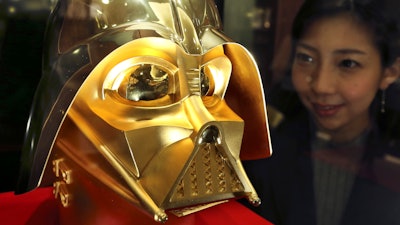 Tokyo gold jeweler Ginza Tanaka employee Momoko Marutani looks at the gold mask of Darth Vader at the jewelry shop in Tokyo, Monday, May 1, 2017. The life-size mask of Star Wars villain Darth Vader will be up for sale for a hefty price of 154 million yen ($1.38 million). The 24-karat mask was created by the gold jeweler to mark the 40th anniversary since the release of the first Star Wars film.