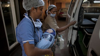 In this Nov. 3, 2015 photo, a newborn baby is transferred to an ambulance at the Akanksha Clinic, one of the most organized clinics in the surrogacy business, in Anand, India.