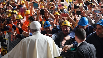 Pope Francis is cheered by workers at the ILVA steel-making company in Genoa, Italy, Saturday, May 27, 2017. Pope Francis has begun a one-day visit to the northern Italian port city of Genoa to meet with workers, poor and homeless people, refugees and prisoners. His opened his visit at ILVA, a troubled steel-making company, where workers in hard hats awaited him. The visit puts a focus on the plight of workers whose lives have been made precarious by years of economic crisis.