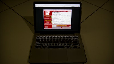 A screenshot of the warning screen from a purported ransomware attack, as captured by a computer user in Taiwan, is seen on laptop in Beijing, Saturday, May 13, 2017. Dozens of countries were hit with a huge cyberextortion attack Friday that locked up computers and held users' files for ransom at a multitude of hospitals, companies and government agencies.