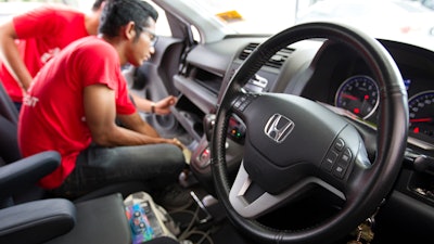 In this Sunday, Nov. 20, 2016, photo, a Honda technician works on an airbag during a free airbag replacement event in Kuala Lumpur, Malaysia. A Malaysian man whose wife's death is one of at least 16 blamed on air bag defects has sued Japanese automaker Honda and the Takata Corp. in a U.S. court, saying he wants the companies to disclose more about the dangers.