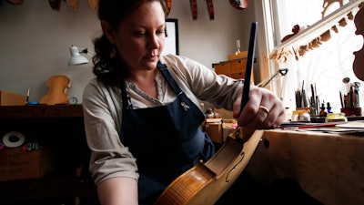Sonja St. John applies varnish on a violin at her workshop in Neenah, Wis., on Thursday, April 27, 2017. Her brother, Jon St. John, died in Iraq in 2007 while serving in the military. Among other things, Sonja has found solace in her career, making and restoring violins.