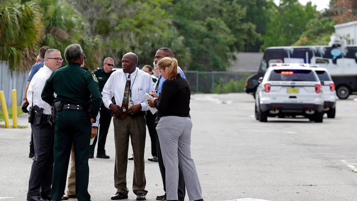 Authorities confer near the scene of a shooting where they said there were multiple fatalities in an industrial area near Orlando, Fla., Monday, June 5, 2017. The Orange County Sheriff's Office said on its official Twitter account that the situation has been contained.