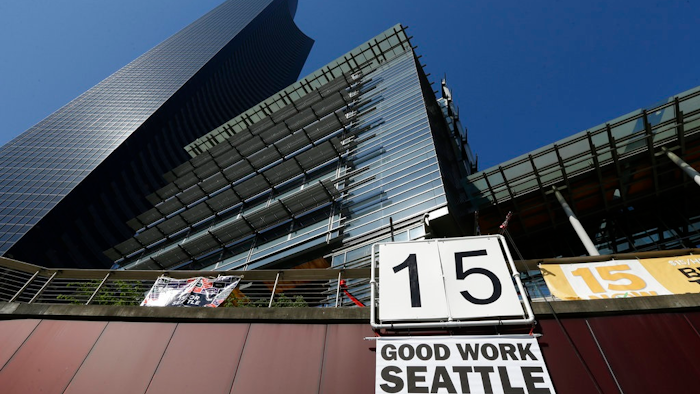 In this June 2, 2014, file photo, a sign that reads '15 Good Work Seattle' is displayed below Seattle City Hall, right, and the Columbia Center building, left, after the Seattle City Council passed a $15 minimum wage measure. A new study says Seattle's $15-an-hour minimum wage law has boosted pay for restaurant industry workers without costing jobs. The report, from the University of California at Berkeley, is certain to add to the debate as activists around the country push for increases in local, state and federal minimum wages.