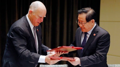 California Gov. Jerry Brown, left, exchanges memorandum of understanding with China's Science and Technology Minister Wan Gang after the Clean Technology signing ceremony at a hotel in Beijing, Tuesday, June 6, 2017.