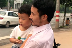 Chinese labor activist Hua Haifeng carries his son as they leave a police station after being released.