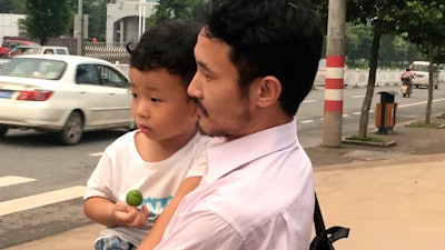 Chinese labor activist Hua Haifeng carries his son as they leave a police station after being released.