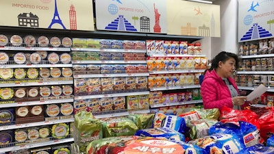 In this file photo taken Friday, March 17, 2017, a vendor takes stock of imported food at a mall in Beijing, China. Food exporters including the United States and Europe are stepping up pressure on China to scale back plans for intensive inspections of imports that they say will hamper access to its fast-growing market.