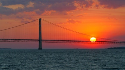 In this May 31, 2002 file photo, the sun sets over the Mackinac Bridge and the Mackinac Straits as seen from Lake Huron. The bridge is the dividing line between Lake Michigan to the west and Lake Huron to the east. Michigan's attorney general, Republican Bill Schuette, called Thursday, June 29, 2017 for shutting down the nearly 5-mile-long (8-kilometer-long) section of Enbridge Inc.'s Line 5 under the Straits of Mackinac.