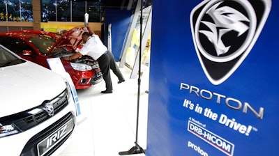 A man inspects Proton's model 'Saga' displayed inside a showroom in Kuala Lumpur, Malaysia Friday, June 23, 2017. The Chinese owner of Sweden's Volvo Cars says it has signed the final contract to buy a stake in Malaysian automaker Proton, gaining a platform to expand in Southeast Asia.