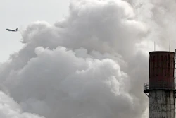 In this Feb. 28, 2017 file photo, a passenger airliner flies past steam and white smoke emitted from a coal-fired power plant in Beijing. President Donald Trump's pullback from a global climate pact could accelerate China's unlikely ascent toward leadership in stemming global warming and promoting green technology, and on global matters far removed from the environment.