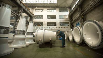 In this Nov. 9, 2015 photo, a worker inspects wind turbine parts at a Goldwind wind turbine factory in Beijing. Increasing amounts of green energy have gone unused in China as it struggles to integrate wind and solar power into a dated electricity network dominated by coal.