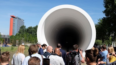 People look at a hyperloop test facility unveiled by a tech startup and a construction company in Delft, Netherlands, Thursday, June 1, 2017. The 30 meter (100 foot) long white steel tube will be used to help develop the futuristic high-speed transportation system. The tube is a first step toward developing the system in the Netherlands, a key European transportation transport hub.
