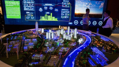 In this photo taken Wednesday, June 7, 2017, visitors look at a model of a city run on clean energy during an international clean energy conference held in Beijing, China. Energy ministers from around the world gathered in Beijing this week to report increased spending to help counter climate change. Yet one prominent voice, that of U.S. Energy Secretary Rick Perry, delivered a starkly countervailing message as the Trump administration seeks to roll back spending on clean energy and promote fossil fuels.