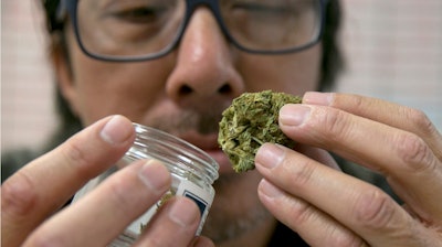 Joseph Hough, an employee at the Canna Care medical marijuana dispensary, displays a pre-packaged marijuana bud Wednesday, June 14, 2017, in Sacramento, Calif. Tucked in the state budget agreement reached between Gov. Jerry Brown and top legislative Democrats, are standards to merge the state's new voter-approved recreational marijuana law with the long-standing medical marijuana program. Lawmakers are expected to vote on the budget plan, Thursday.