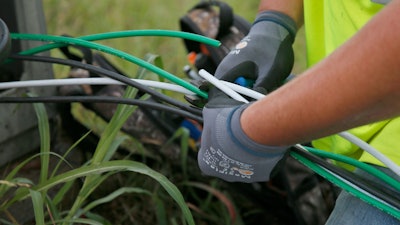 In this Thursday, June 22, 2017 photo, Noah Zeigler works at installing new aluminum wiring at a streetlight in Tulsa, Okla. The city has lost 33 miles of streetlight wiring to thieves stealing copper wire.