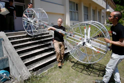 Members of Cartivator carry propellers of the test model flying car in Toyota, central Japan, Saturday, June 3, 2017. Cartivator Resource Management, in which Toyota invested 42.5 million yen ($386,000), showed reporters Saturday a test flight of a concoction of aluminum framing and propellers. It took off several times, hovering at eye level for a few seconds, before falling to the ground.