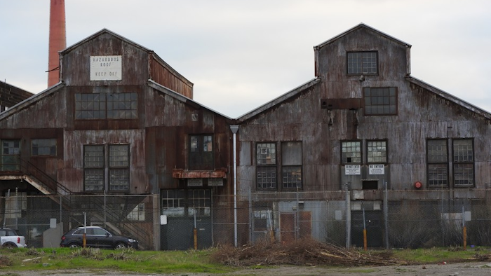 Abandoned industrial buildings at San Francisco’s Pier 70, with a smokestack in the background.