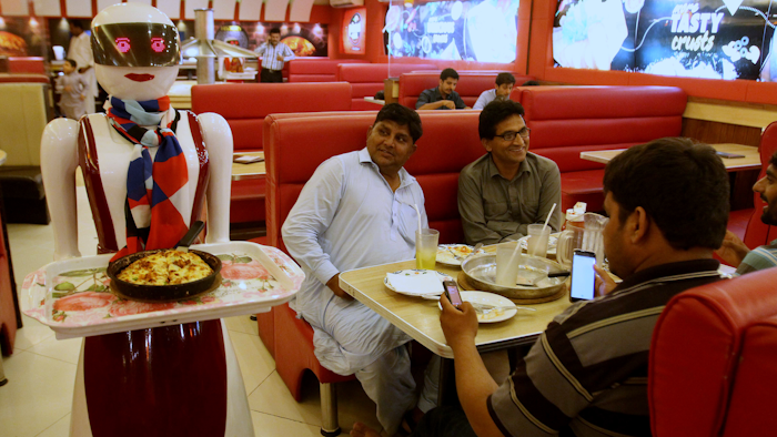 A robot waitress serves food to customers.