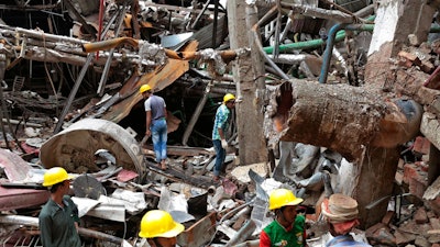 Bangladeshi firefighters and rescuers stand on the debris after a Monday evening boiler explosion at a garment factory owned by export-oriented Multifabs Ltd. at Kashimpur area in Gazipur district, outside capital Dhaka, Bangladesh, Tuesday, July 4, 2017.