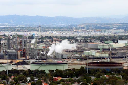 This May 25, 2017 aerial photo shows the Standard Oil Refinery in El Segundo, Calif., with Los Angeles International Airport in the background and the El Porto neighborhood of Manhattan Beach, Calif., in the foreground. A plan to extend California's cap-and-trade program for another decade looks beyond cutting greenhouse gas emissions and takes aim at toxic air in the polluted neighborhoods around refineries and factories.