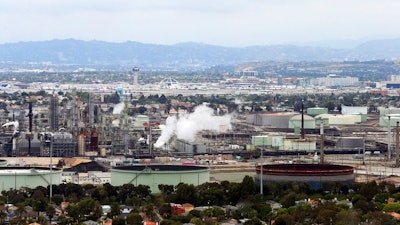 This May 25, 2017 aerial photo shows the Standard Oil Refinery in El Segundo, Calif., with Los Angeles International Airport in the background and the El Porto neighborhood of Manhattan Beach, Calif., in the foreground. A plan to extend California's cap-and-trade program for another decade looks beyond cutting greenhouse gas emissions and takes aim at toxic air in the polluted neighborhoods around refineries and factories.