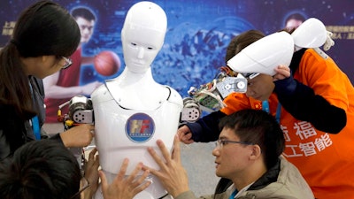 In this Oct. 21, 2016, file photo, Chinese students work on the Ares, a humanoid bipedal robot designed by them with fundings from a Shanghai investment company, displayed during the World Robot Conference in Beijing. China's government announced Thursday, July 21, 2017, a goal of transforming the country into a global leader in artificial intelligence in just over a decade, putting additional political support behind growing investment by Chinese companies in developing self-driving cars and other advances.