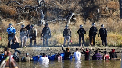 In this Nov. 2, 2016 file photo, protesters demonstrating against the expansion of the Dakota Access pipeline wade in cold creek waters confront local police near Cannon Ball, N.D. Industry officials say protests like the one involving the disputed pipeline may be commonplace in the future. The recently completed $3.8 billion pipeline that's opposed by American Indian tribes and others was discussed Wednesday, July 19, 2017, at an annual oil industry conference in Bismarck with a panel dissecting what was learned from the nearly year-long struggle over building it in North Dakota.