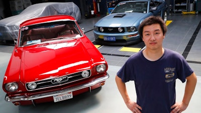 In this Wednesday, June 28, 2017, photo, Guo Xin poses with his 1966 MT GT Fastback, left, and 2005 GT convertible at his garage in Beijing. A former race car driver, Guo finds Mustangs tougher and more fun to drive than European or Japanese sports cars.