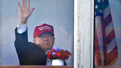 President Donald Trump waves to spectators as he watches the third round of the U.S. Women's Open Golf tournament from his observation booth, Saturday, July 15, 2017, in Bedminster, N.J.