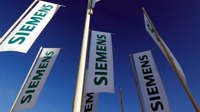 In this Jan. 23, 2013 file photo flags of German engineering conglomerate Siemens AG fly during an annual shareholder meeting in Munich, southern Germany. German industrial conglomerate Siemens AG says Friday, July 21, 2017 it’s halting deliveries of power generation equipment to state-controlled companies in Russia and selling its stake in a Russian company that offers services for power plant control systems.