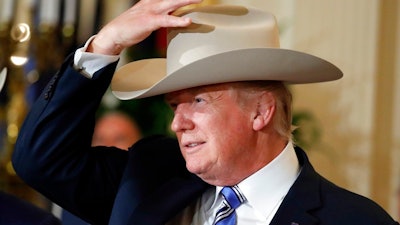 President Donald Trump tries on a Stetson hat during a 'Made in America,' product showcase featuring items created in each of the U.S. 50 states, Monday, July 17, 2017, at the White House in Washington. Stetson is base in Garland, Texas.