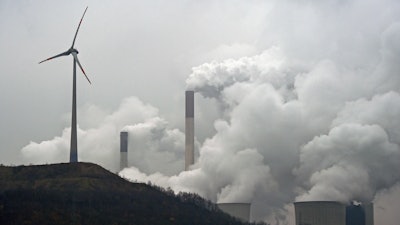 In this file photo dated Monday, Dec. 1, 2014, a wind turbine overlooks the coal-fired power station in Gelsenkirchen, Germany. The European Environment Agency released a report late Sunday July 9, 2017, saying coal-fired power plants are responsible for the most water and air pollution on the European continent, with Britain among the top polluters, followed by Germany, France and Poland.