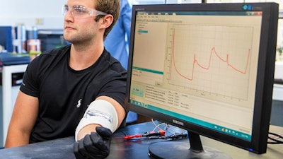 Vanderbilt undergraduate Thomas Metke demonstrates the ultrathin energy harvesting device which is taped across his elbow. As he flexes his arm the current the device generates is displayed on the computer display.