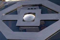 The concentrating photovoltaic system showing the top lenslet; the little black square visible near the middle is the solar cell and the lines running away from it are the contact wires.