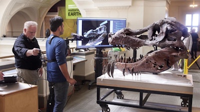 Researchers demonstrate their scanning technique, with a user holding a monopod-mounted Kinect at close range from a scanning T-Rex skull.