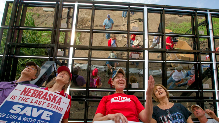 In this July 29, 2017 photo, Jane Kleeb, president of Bold Alliance, center, landowner Chris Carlson, second right and volunteers, pose for a photo under an array of solar panels they built in a corn field belonging to the Carlsons of Silver Creek, Ne., in the proposed path of the Keystone XL pipeline. Despite new uncertainty over whether TransCanada, the builder of the Keystone XL pipeline will continue the project, longtime opponents in Nebraska aren't letting their guard down and neither are law enforcement officials who may have to react to protests if it wins approval.