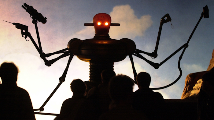 In this Tuesday, Aug. 1, 2000 file photo, visitors of the world exhibition Expo 2000 stand in front of a robot display at the 'Planet of Visions' exhibit at the Expoground in Hanover, northern Germany. Use of robotics in manufacturing and other sectors is increasing in countries from the United States and China, and robots have long been embraced for a variety of uses in countries such as Japan. There also has long been “robophobia,” stoked by science fiction writers and moviemakers.