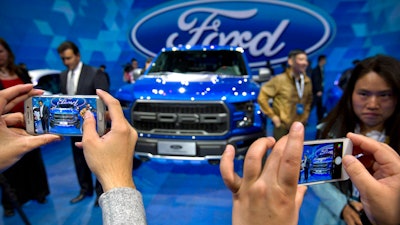 1 0 In this April 23, 2016, photo, attendees take smartphone photos at a promotional event for Ford Motor Company ahead of the Auto China car show in Beijing. Ford Motor Co. announced an agreement Tuesday, Aug. 22, 2017 with a Chinese partner to look into forming a joint venture to develop and manufacture electric cars in China.