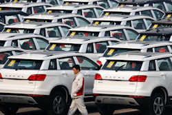 In this Feb. 19, 2017, file photo, a worker walks past Haval SUV models parked outside the Great Wall Motors assembly plant in Baoding in north China's Hebei province. Chinese SUV maker Great Wall Motors is considering making a bid to acquire Fiat Chrysler's Jeep unit, two employees of the Chinese company said Monday, Aug. 21, 2017 in an ambitious new move for the country's fast-growing domestic auto brands. Great Wall has yet to make a formal announcement of its interest in Jeep but a possible acquisition would be in line with chairman Wang Jianjun's goal, announced in February, of becoming the top specialty SUV producer by 2020.