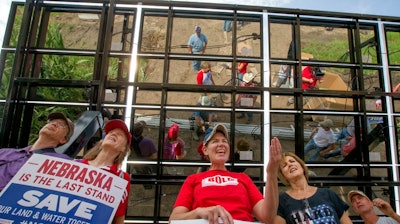 In this July 29, 2017 photo, Jane Kleeb, president of Bold Alliance, center, landowner Chris Carlson, second right and volunteers, pose for a photo under an array of solar panels they built in a corn field belonging to the Carlsons of Silver Creek, Ne., in the proposed path of the Keystone XL pipeline. Despite new uncertainty over whether TransCanada, the builder of the Keystone XL pipeline will continue the project, longtime opponents in Nebraska aren't letting their guard down and neither are law enforcement officials who may have to react to protests if it wins approval.