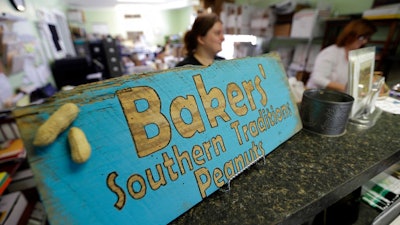In this photo taken Friday, July 14, 2017 Leslie Briley, background, helps a customer at Bakers' Southern Tradition Peanuts in Roxobel, N.C. located in Bertie County. Riley grew up in Roxobel, a town of 220 people in northwestern Bertie County, returned after graduating from college in Wilson and now works at a growing family-owned peanut business.